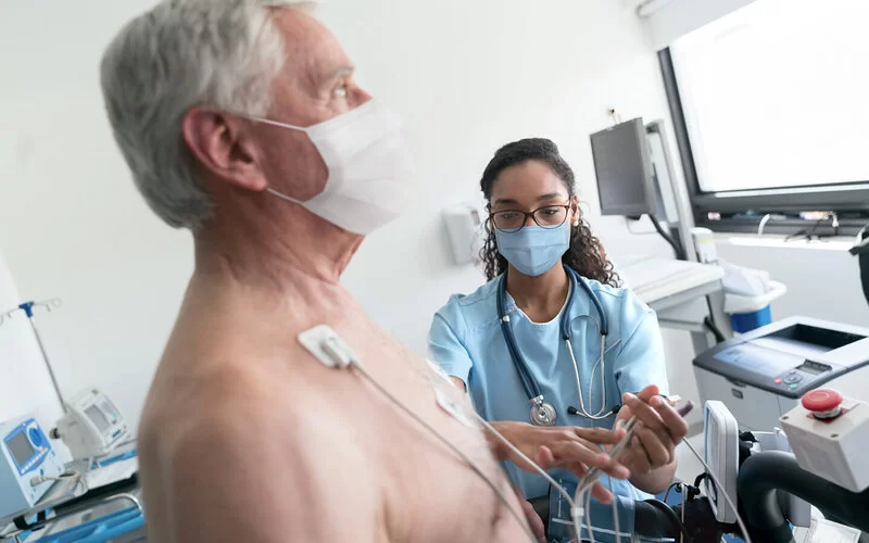 Eine medizinische Fachangestellte überwacht einen Patienten beim Belastungs-EKG.