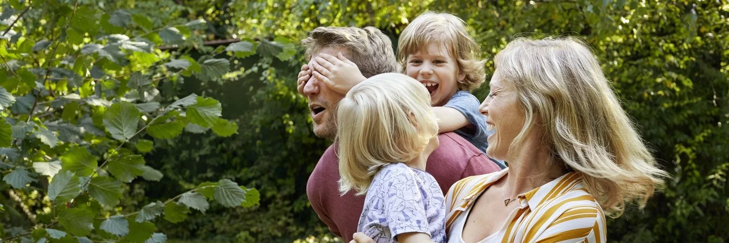 Familie die zusammen im Grünen lacht.