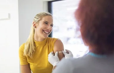 Eine junge Frau wird in den linken Oberarm geimpft. 
