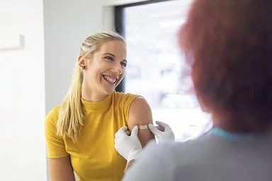 Eine junge Frau wird in den linken Oberarm geimpft.