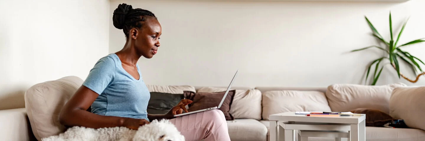 Eine junge Frau sitzt mit ihrem Laptop im Wohnzimmer und sieht sich ihre ePA mit dem Desktop Client an.
