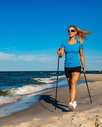 Eine Frau in einem kurzen Oberteil macht Nordic-Walking am Strand.
