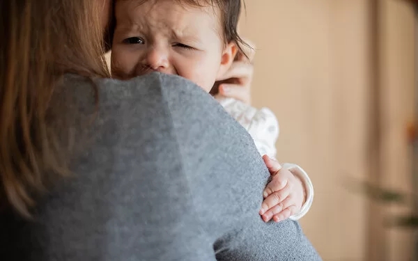 Eine Frau hält ein weinendes Baby auf dem Arm.