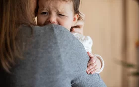 Eine Frau hält ein weinendes Baby auf dem Arm.