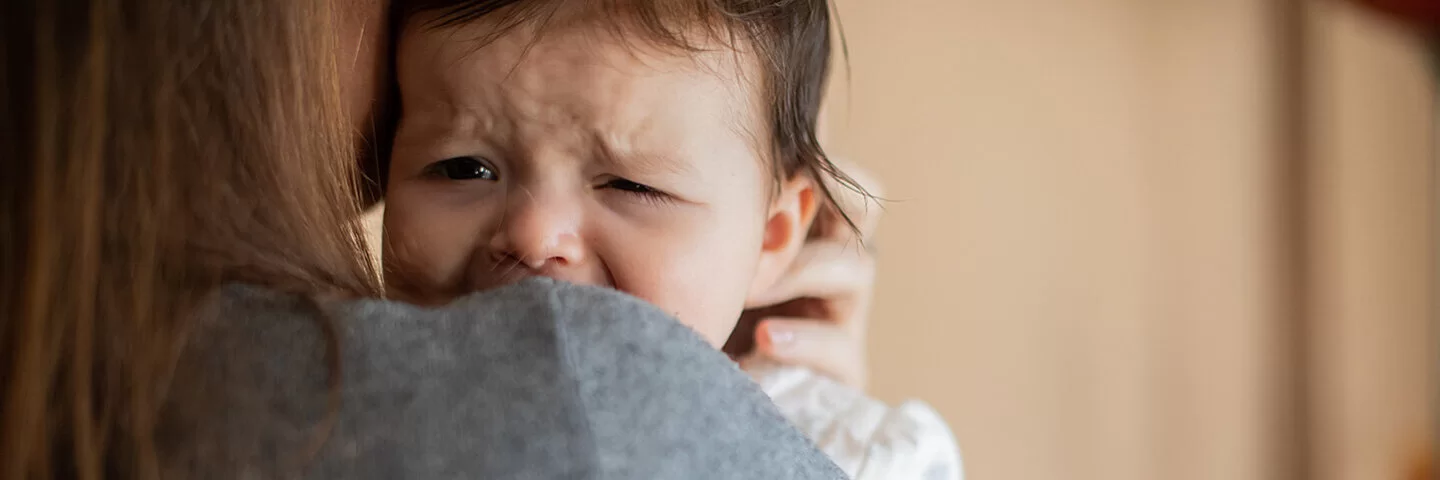 Eine Frau hält ein weinendes Baby auf dem Arm.