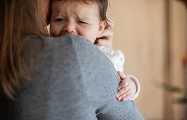 Eine Frau hält ein weinendes Baby auf dem Arm.