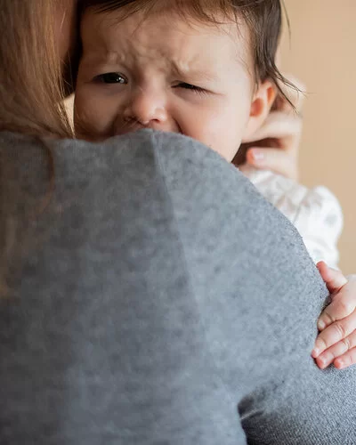 Eine Frau hält ein weinendes Baby auf dem Arm.