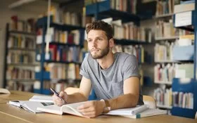 Student sitzt in Bibliothek und denkt nach, ob er wirklich so schlau ist.