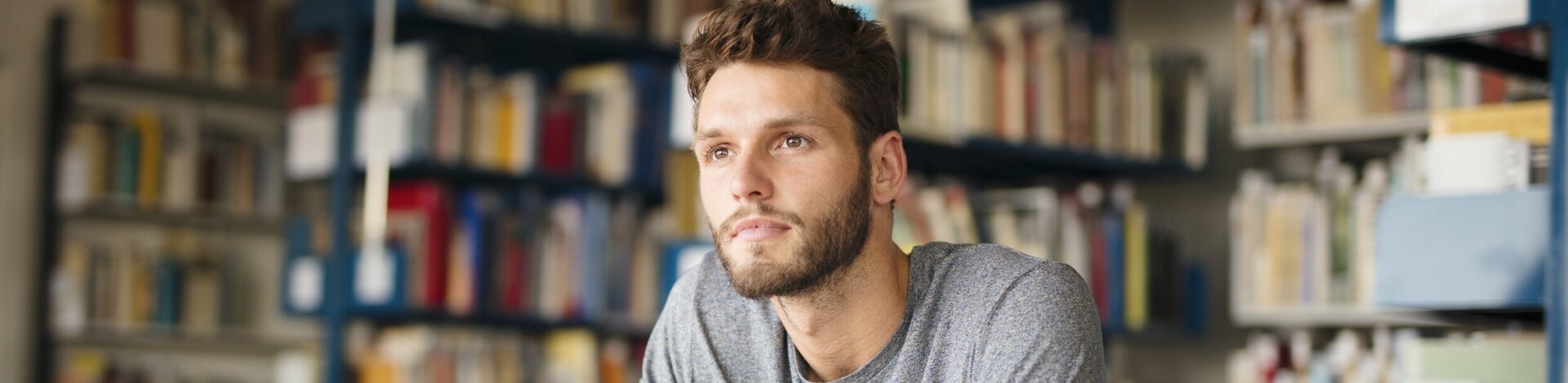 Student sitzt in Bibliothek und denkt nach, ob er wirklich so schlau ist.