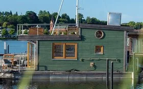 Ein Hausboot liegt an einem Bootssteg an der Küste.