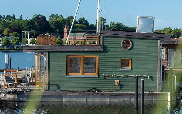 Ein Hausboot liegt an einem Bootssteg an der Küste.