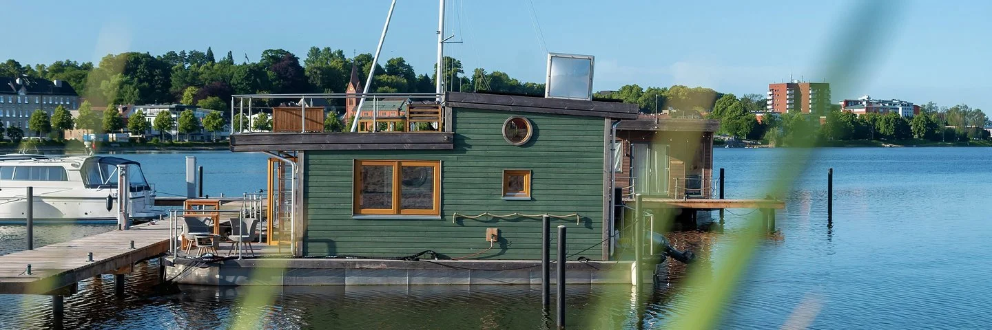 Ein Hausboot liegt an einem Bootssteg an der Küste.