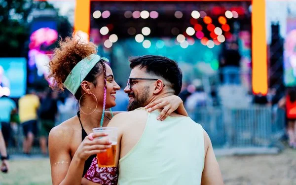 Ein glückliches Paar umarmt sich vor einer Musikbühne stehend und inmitten einer Menschenmenge.