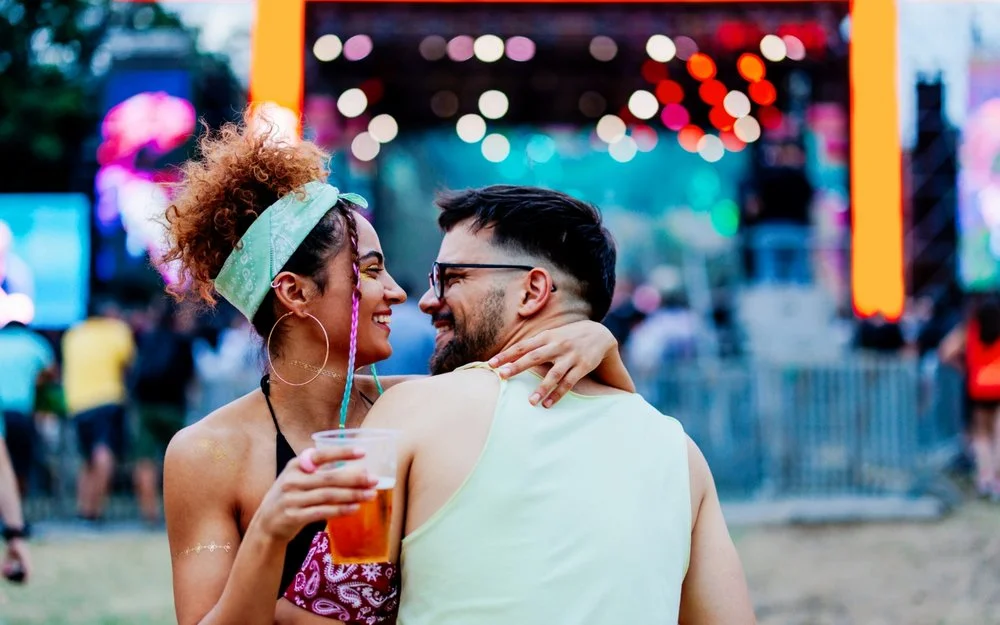 Ein glückliches Paar umarmt sich vor einer Musikbühne stehend und inmitten einer Menschenmenge.