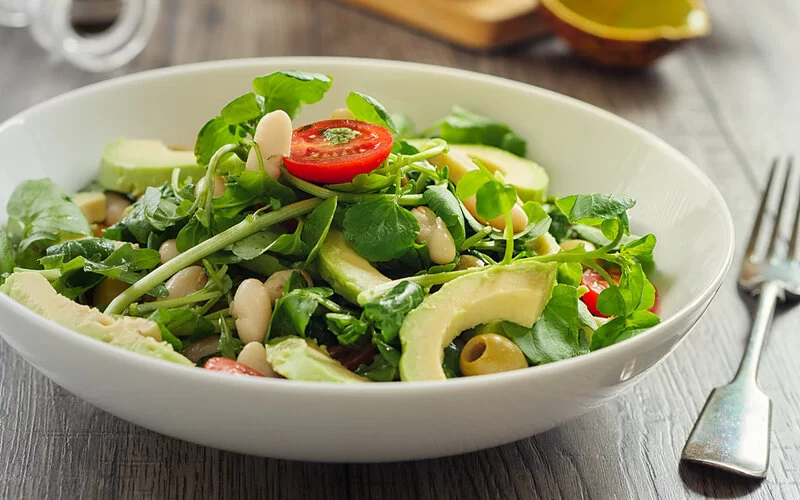 Gesunde Brunnenkresse in einem Salat mit Tomate und Avocado.