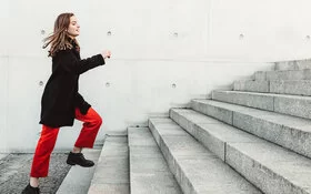 Körperlich fitte Frau läuft Treppen im Alltag ohne Anstrengung hoch.