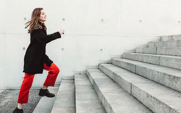Körperlich fitte Frau läuft Treppen im Alltag ohne Anstrengung hoch.