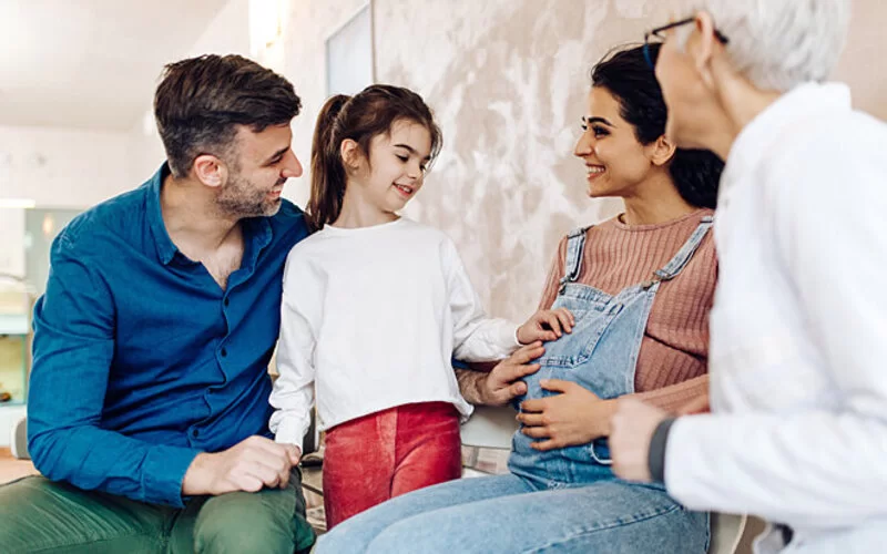 Hebamme berät junge Familie bei ihrem Hausbesuch.