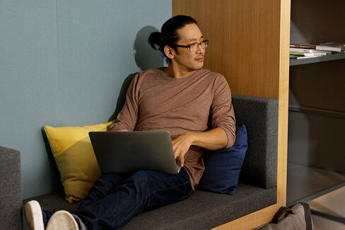 Ein Mann sitzt auf dem Sofa und arbeitet mit dem Laptop. Als Selbstständiger profitiert er von flexiblen Beiträgen zur Krankenkasse.