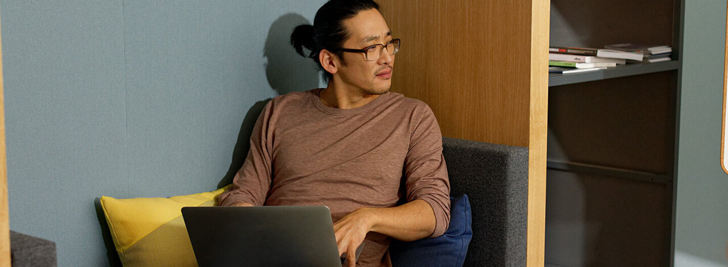 Ein Mann sitzt auf dem Sofa und arbeitet mit dem Laptop. Als Selbstständiger profitiert er von flexiblen Beiträgen zur Krankenkasse.
