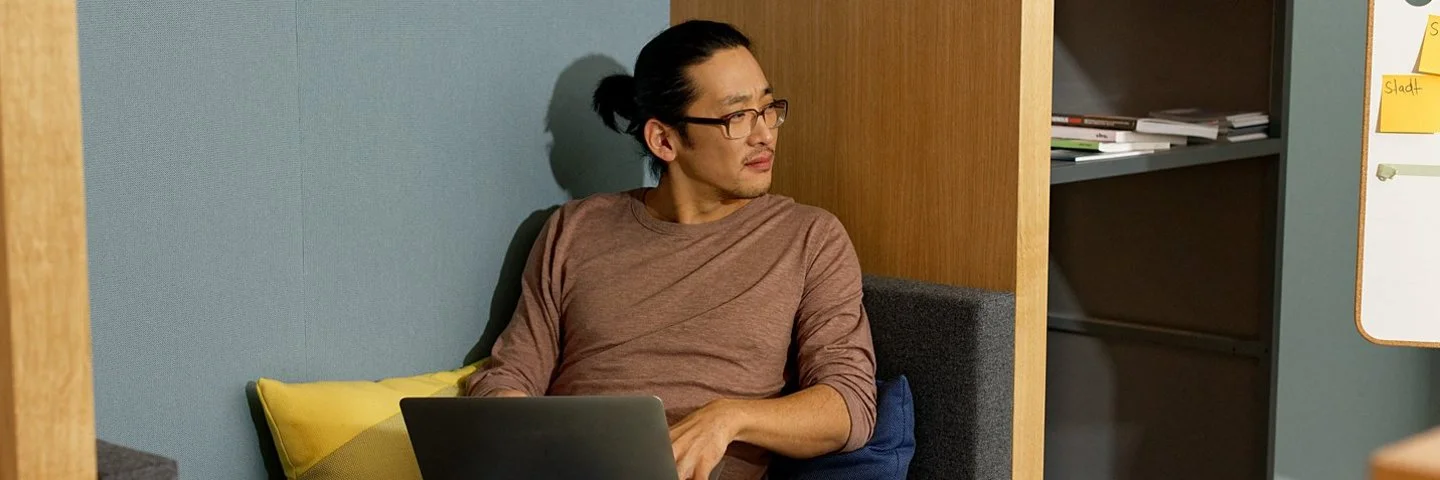 Ein Mann sitzt auf dem Sofa und arbeitet mit dem Laptop. Als Selbstständiger profitiert er von flexiblen Beiträgen zur Krankenkasse.