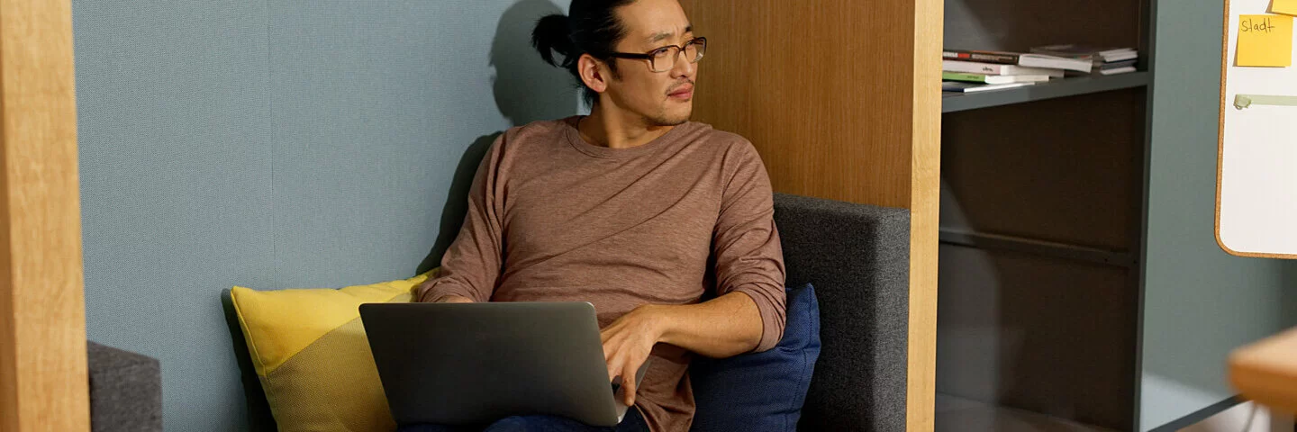 Ein Mann sitzt auf dem Sofa und arbeitet mit dem Laptop. Als Selbstständiger profitiert er von flexiblen Beiträgen zur Krankenkasse.