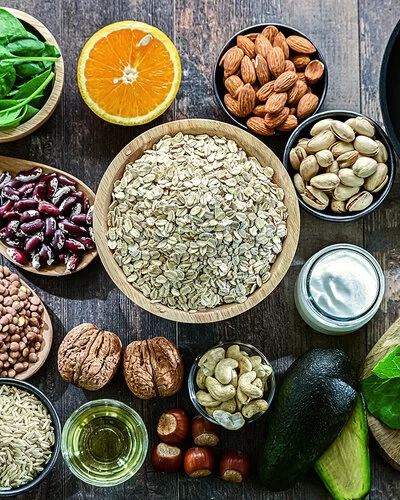 Auf einem Tisch sind Hülsenfrüchte, Salat, Gemüse, Obst, Lachs und Vollkornbrot angerichtet.