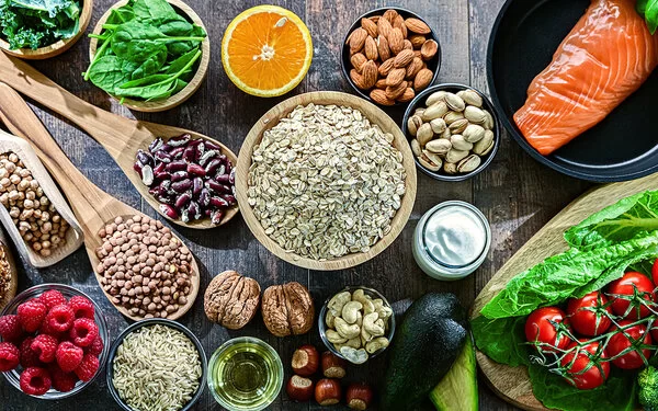 Auf einem Tisch sind Hülsenfrüchte, Salat, Gemüse, Obst, Lachs und Vollkornbrot angerichtet.