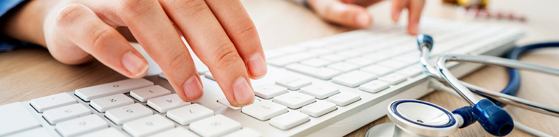 Eine Ärztin tippt auf eine Tastatur. Daneben liegt ein Stethoskop. Das Fachärzteteam von AOK-Clarimedis ist per E-Mail erreichbar.