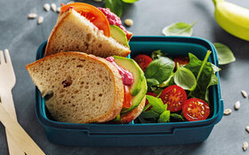 Zwei Scheiben Brot mit Avocado, Tomaten und Basilikum – ein gesundes Pausenbrot.
