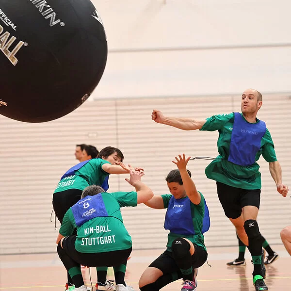 Ein Sportteam spielt Kin-Ball in einer Sporthalle.