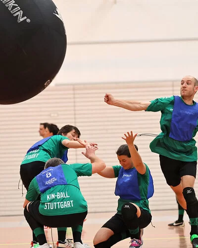 Ein Sportteam spielt Kin-Ball in einer Sporthalle.