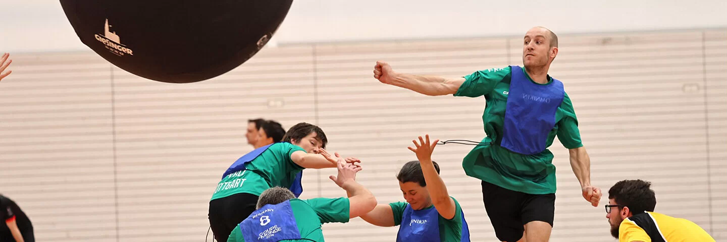 Ein Sportteam spielt Kin-Ball in einer Sporthalle.