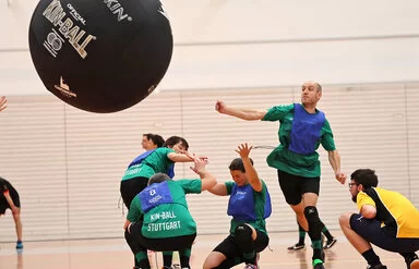 Ein Sportteam spielt Kin-Ball in einer Sporthalle.