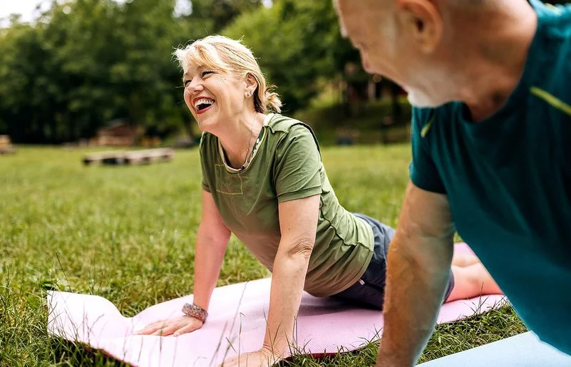 Ein sportlich gekleidetes Paar praktiziert Yoga im Park.