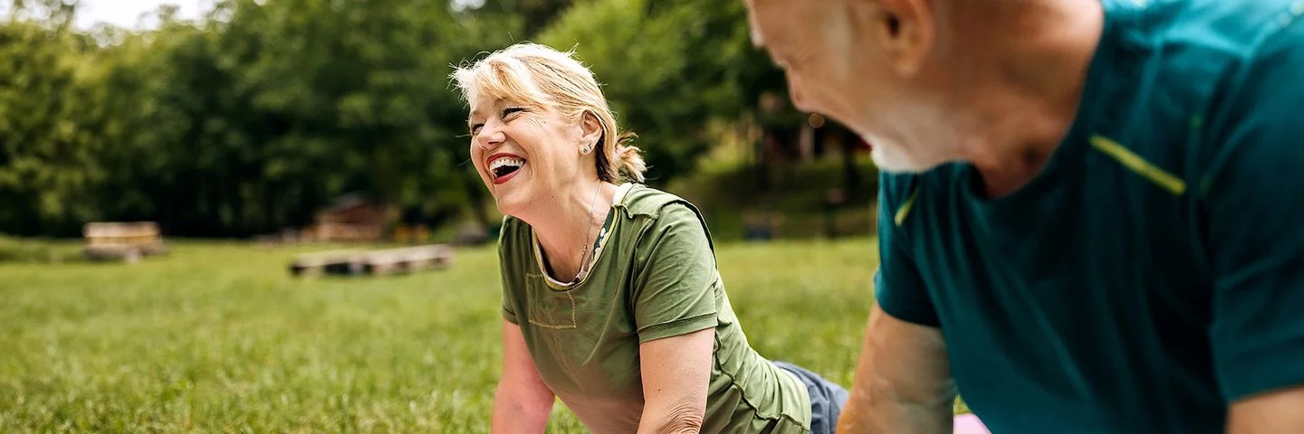 Ein sportlich gekleidetes Paar praktiziert Yoga im Park.