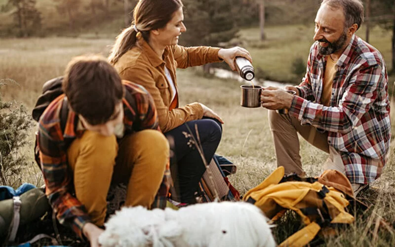 Eine Familie macht eine Pause auf ihrer Wandertour und trinkt Tee.