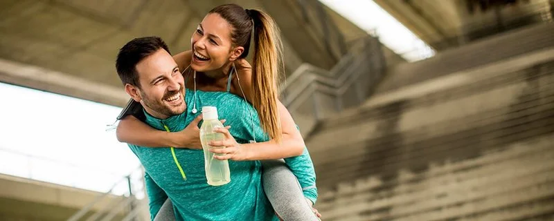 Ein Sportler trägt seine Sportpartnerin auf dem Rücken.