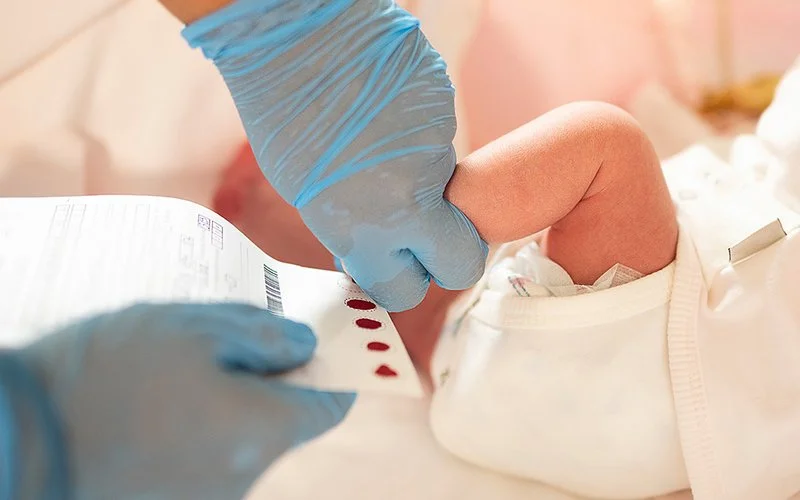 Einem neugeborenen Kind wird Blut aus dem Fuß abgenommen.