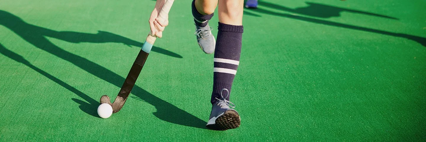 Zwei Damenmannschaften laufen mit Feldhockeyschlägern einem Ball hinterher.