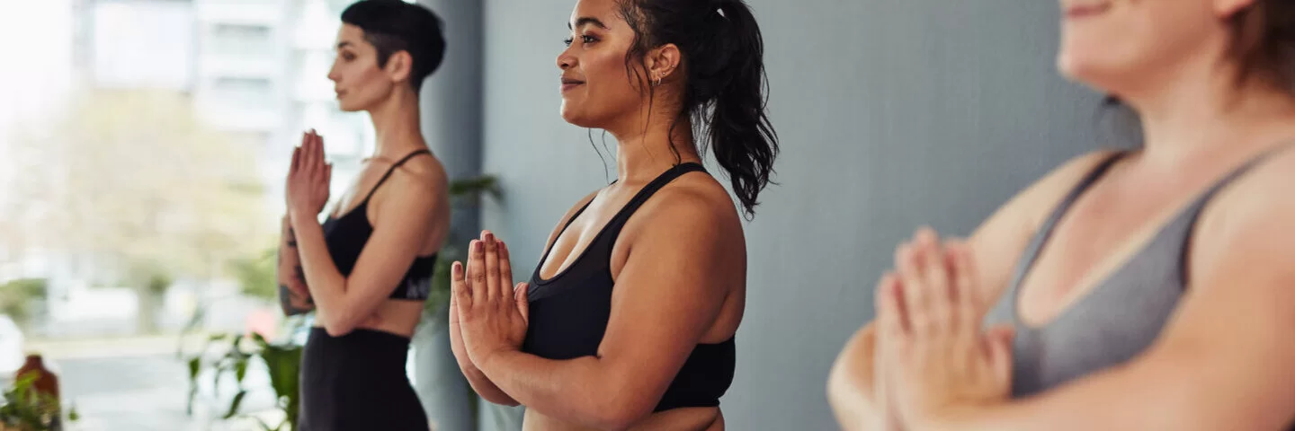 Drei junge Frauen machen Yoga in einem Kurs für junge Mütter.