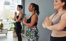 Drei junge Frauen machen Yoga in einem Kurs für junge Mütter.
