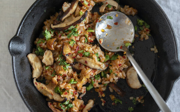 Veganes Pilzgericht mit Steinpilzen, Reis, Chili und Kräutern serviert in einer schwarzen Pfanne