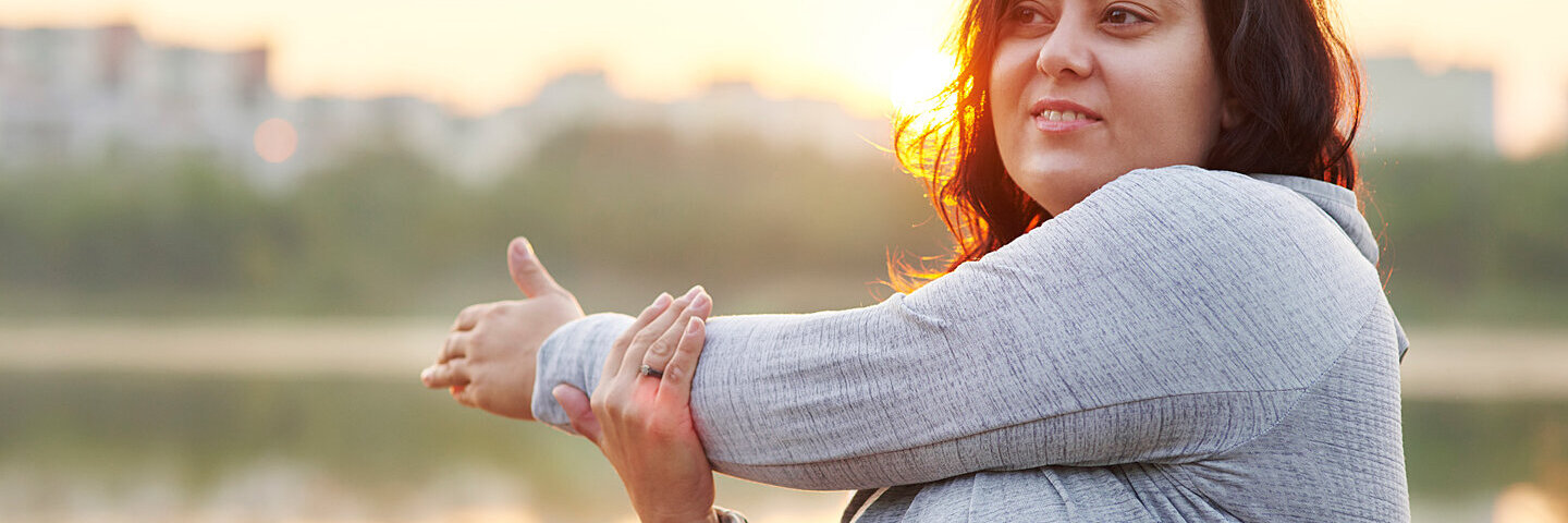 Eine Frau mit Diabetes und Depressionen treibt Sport und dehnt sich die Arme.