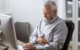 Ein älterer Diabetiker hält sich den Magen, er hat Magenprobleme.