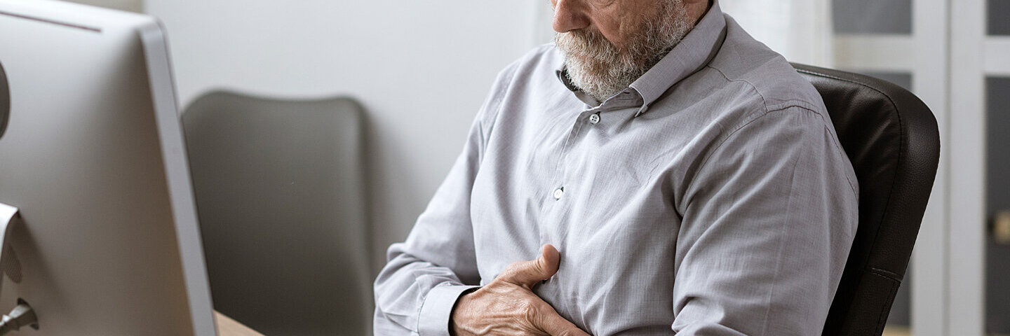 Ein älterer Diabetiker hält sich den Magen, er hat Magenprobleme.