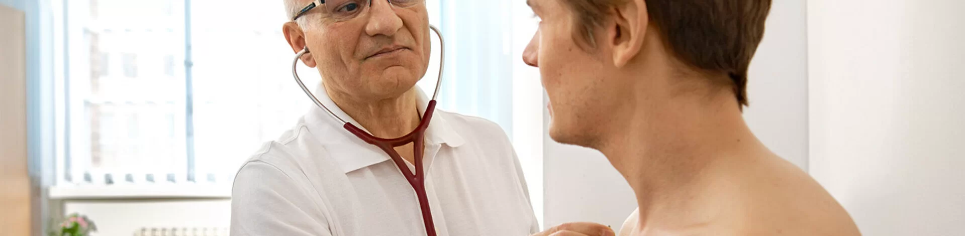 Ein Mann untersucht einen Patienten mit dem Stethoskop. Mit der Hausarztzentrierten Versorgung (HzV) unterstützt die AOK insbesondere chronisch kranke Patienten.