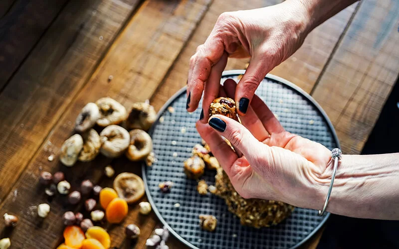 Frau formt mit ihren Händen Energy Balls für eine Schultüte.