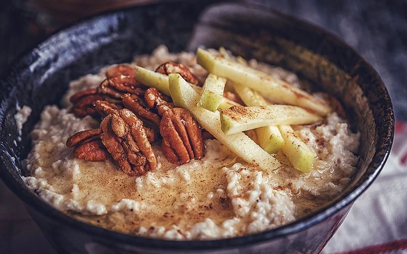 Porridge in einer Schale, das mit Pekannüssen und Birnenstücken dekoriert ist.