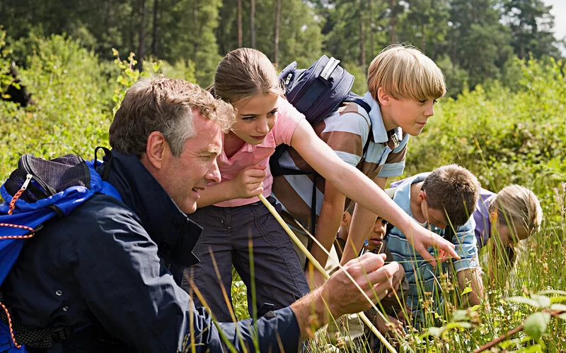 Lehrer mit seiner Schulklasse erkundet die Natur.